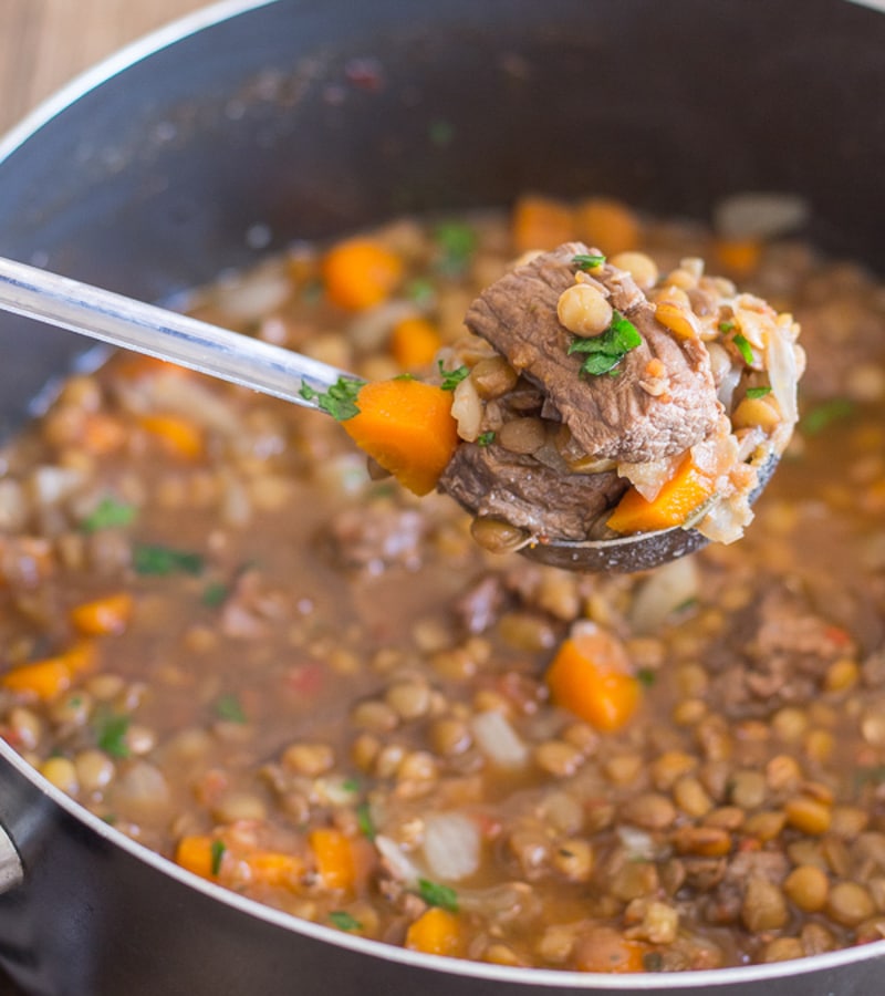 Beef & lentil soup in a pot with some on a ladle.