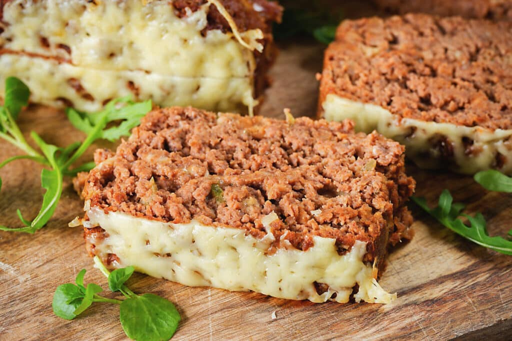 Meatloaf on a wooden board with two slices cut.