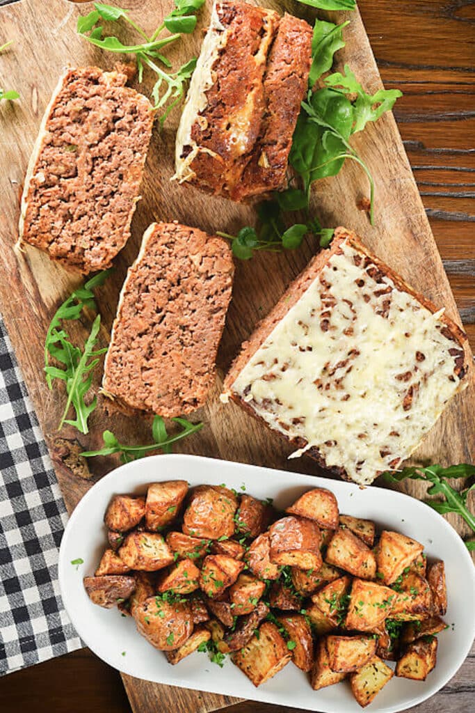 Meatloaf cut with potatoes in a white dish.