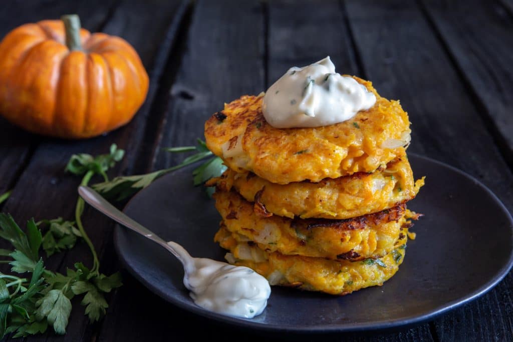 4 Pumpkin fritters stacked with mayo on top.