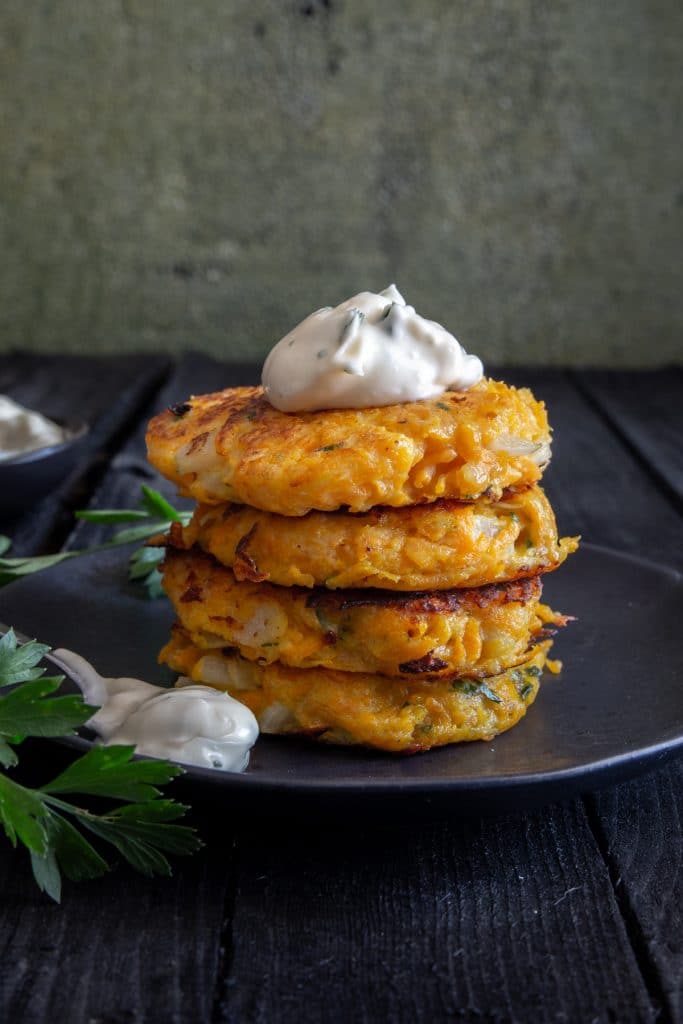 4 Pumpkin fritters stacked with mayo on top.