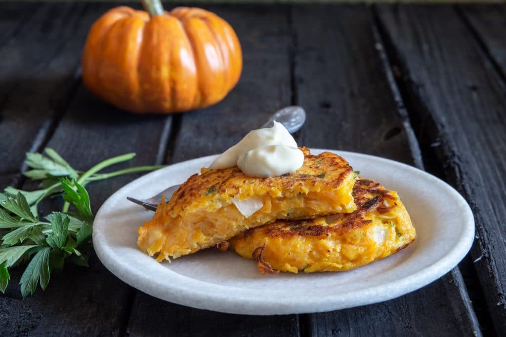 Fritter cut in half on a white plate with a dollop of mayo on top.