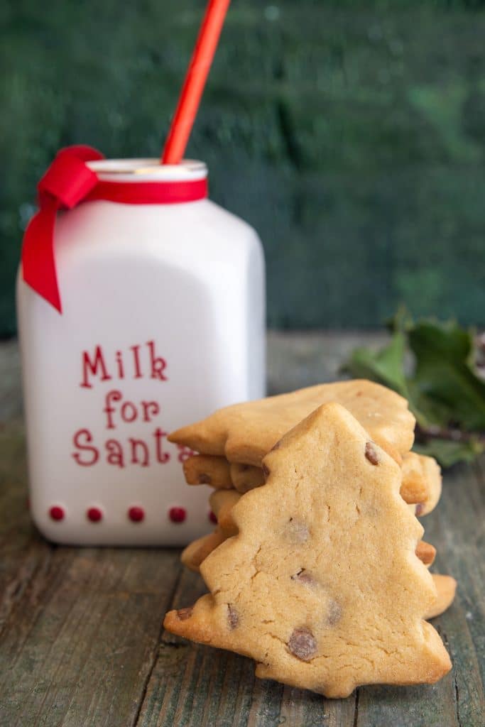 Cookies stacked and one leaning with a milk for santa milk bottle.