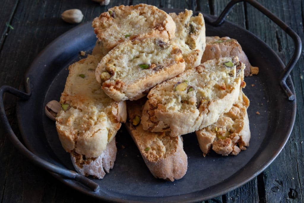 Pistachio biscotti up close on a black plate.