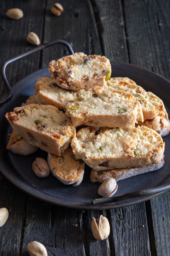 Pistachio biscotti on a black plate.