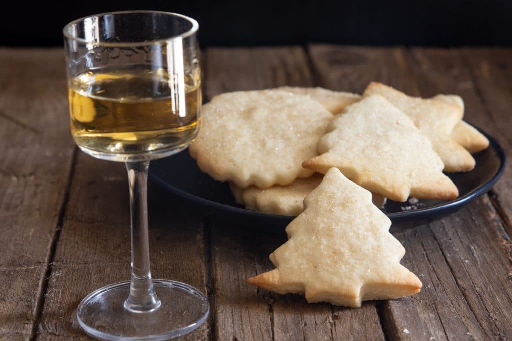 Cookies on a black plate with a glass of rum.