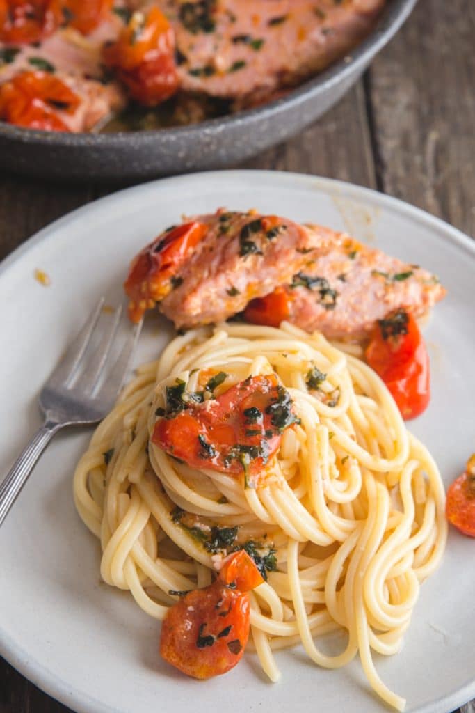Tuna steak with pasta on a white plate.
