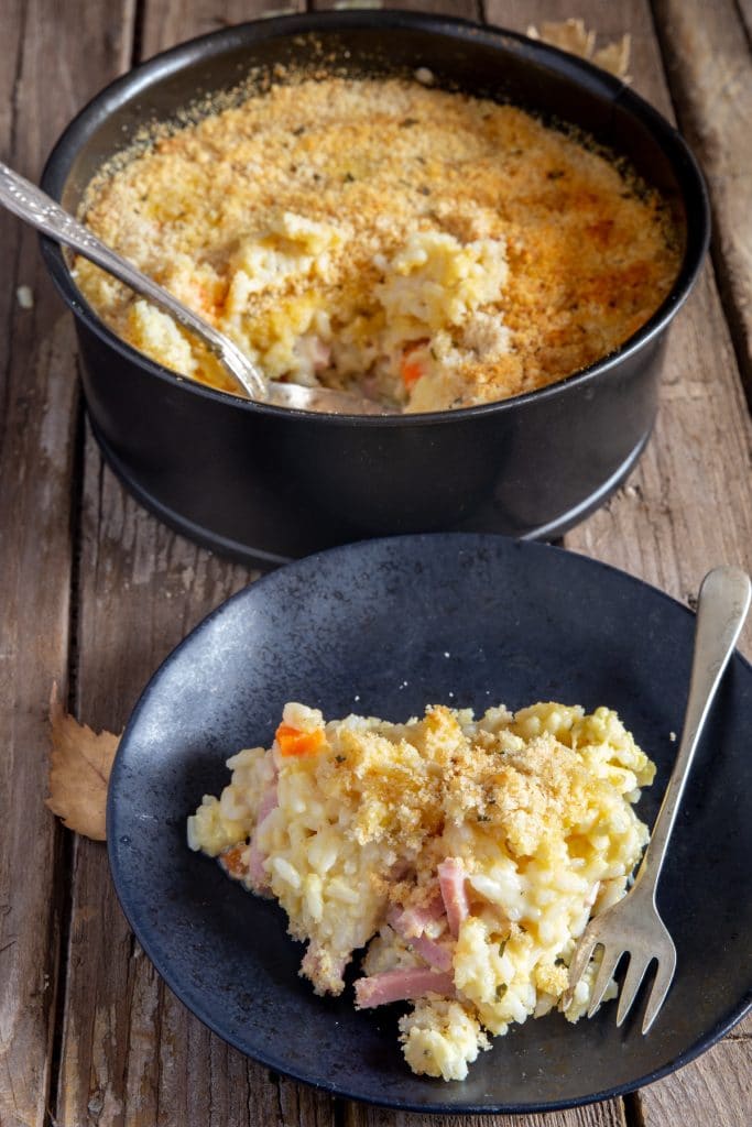 Rice Casserole on a black plate with a silver spoon.