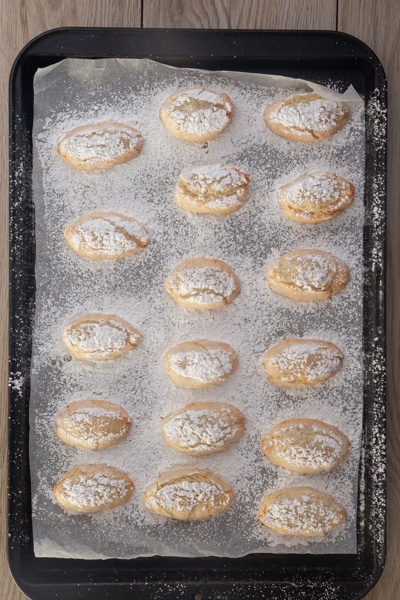The baked Ricciarelli cookies on the cookie sheet.