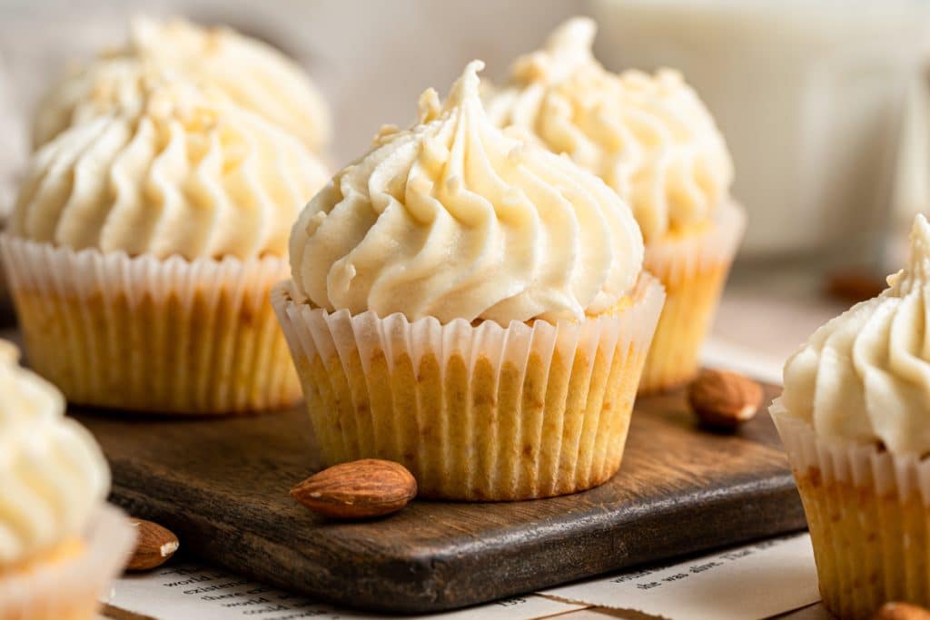 Vanilla almond cupcakes on a wooden board.