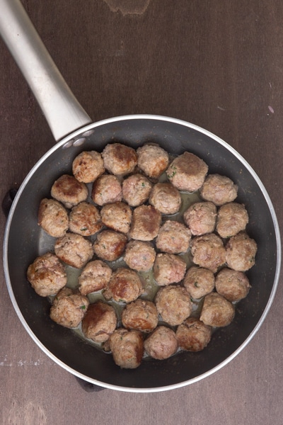 Cooked meatballs in a silver frying pan.