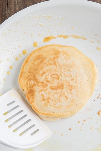 The cooked pancake in a white frying pan.