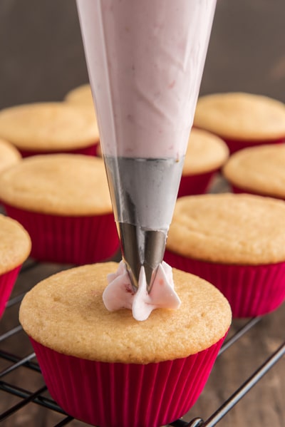Adding the frosting on a cupcake.