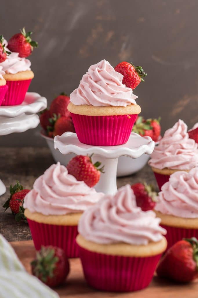Strawberry cupcakes on stands and on a board.