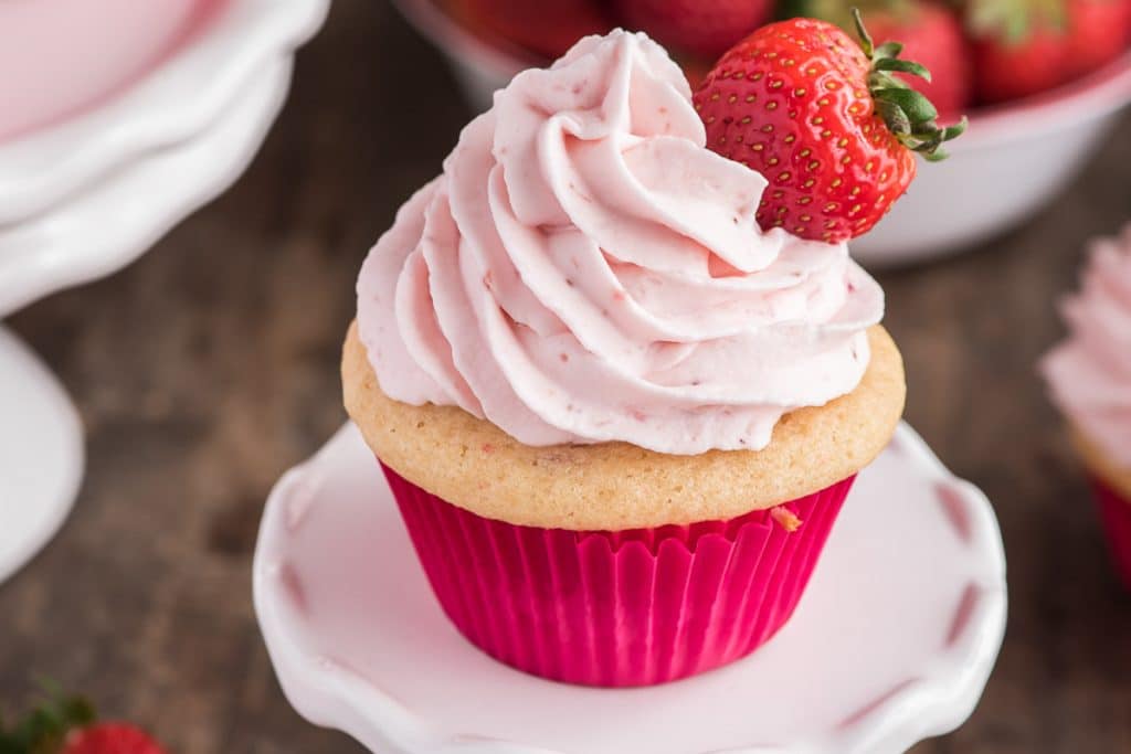 A strawberry cupcake on a white stand.