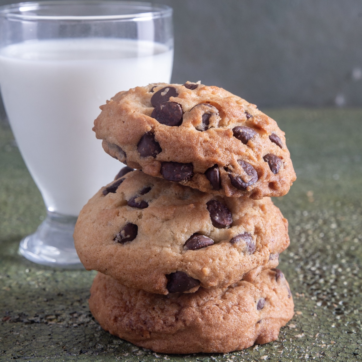 3 cookies stacked with a glass of milk.
