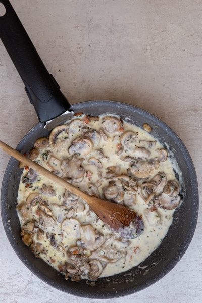 Adding the cream to the cooked mushrooms.