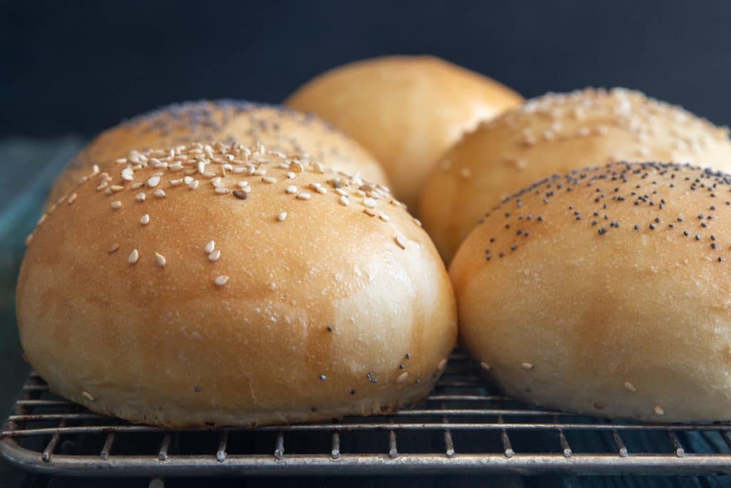 Hamburger buns on a wire rack.