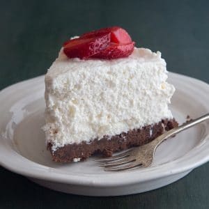 A slice of cheesecake on a white plate with a silver fork.