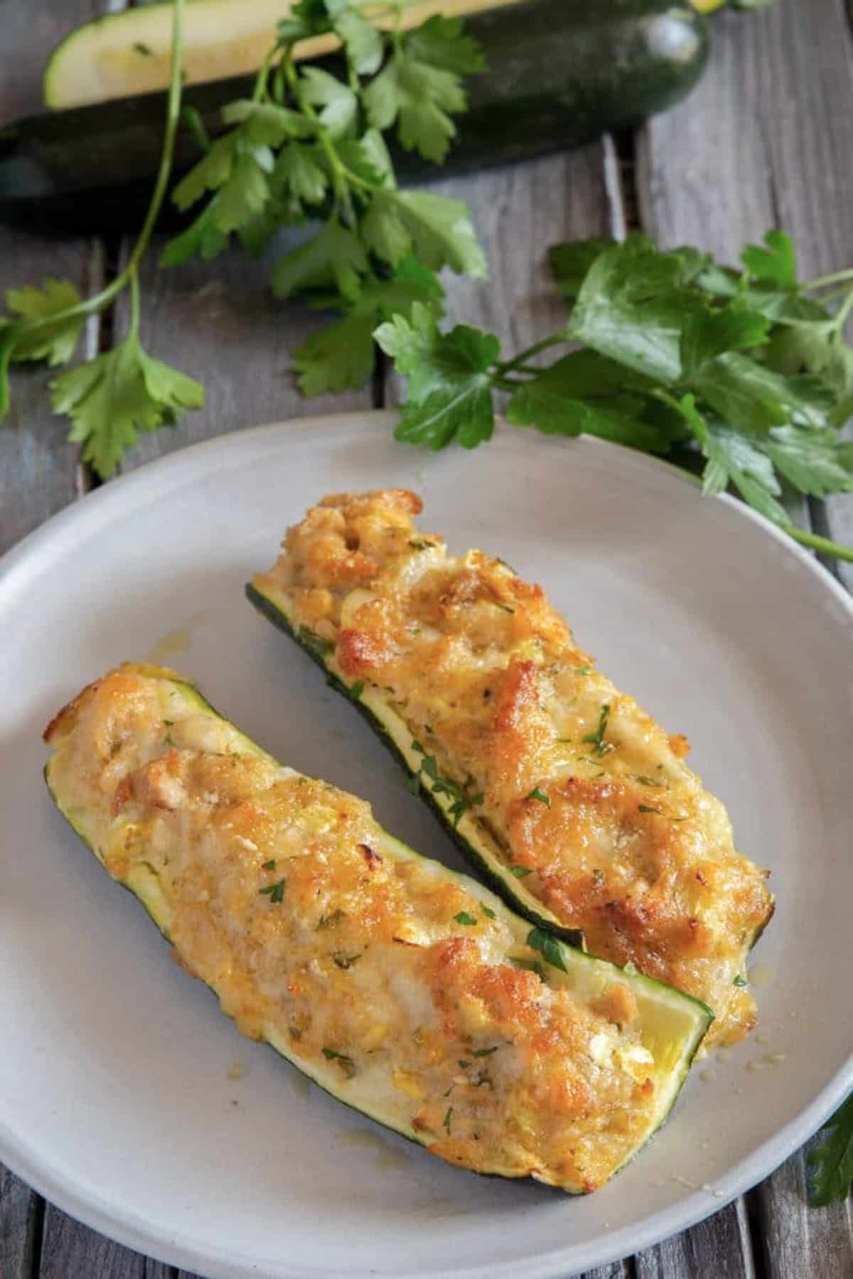 Two stuffed zucchinis on a white plate.