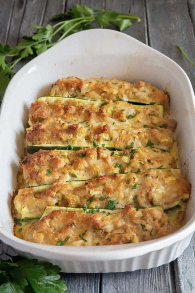 Cooked zucchini boats in a white pan.