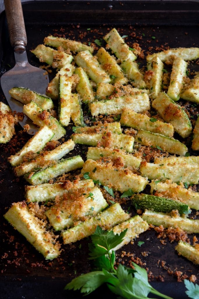 Breaded baked zucchini on a cookie sheet.