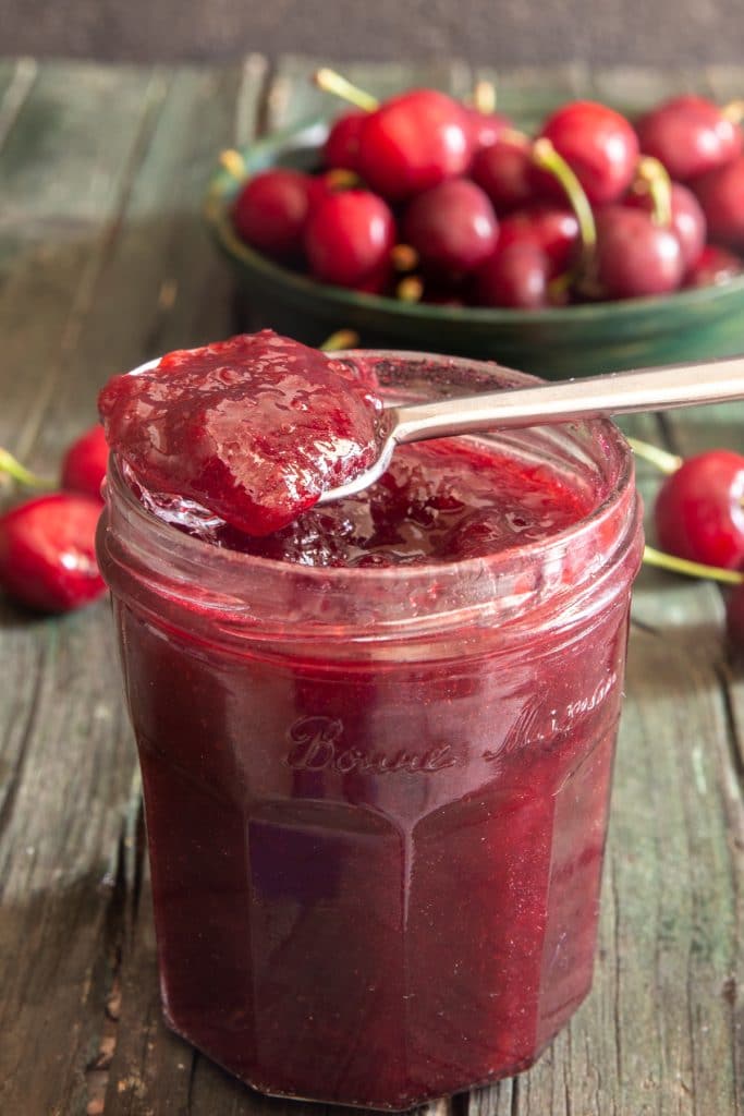 Strawberry jam in a jar and some on a spoon.