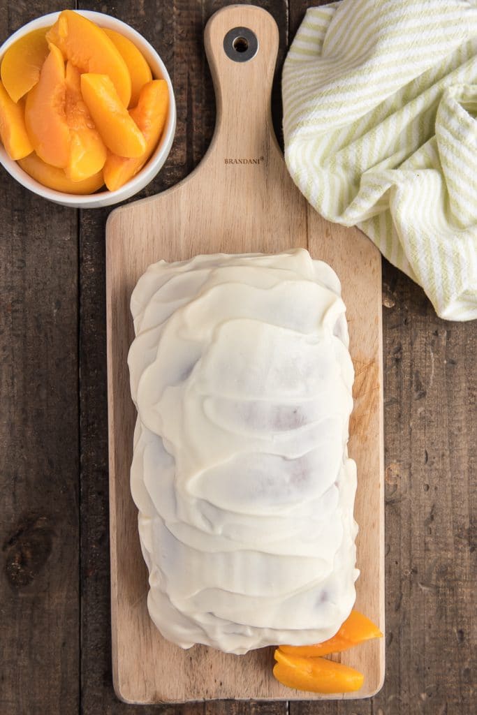 Frosted peach bread on a wooden board.