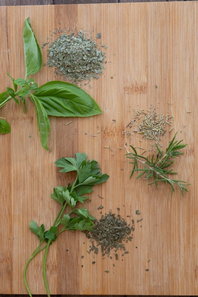 Fresh and dried herbs on a wooden board.