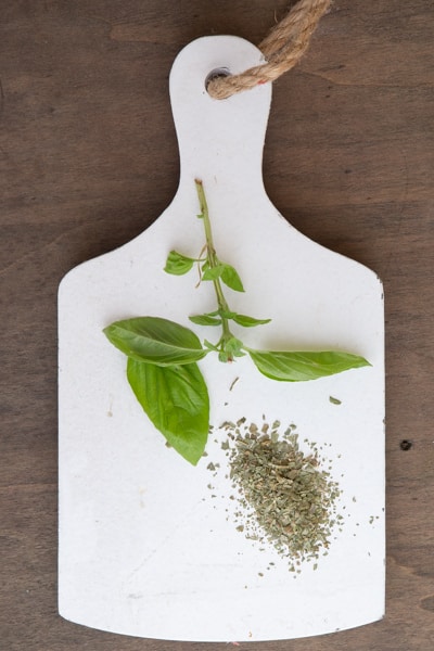 Basil fresh and dried on a white board.