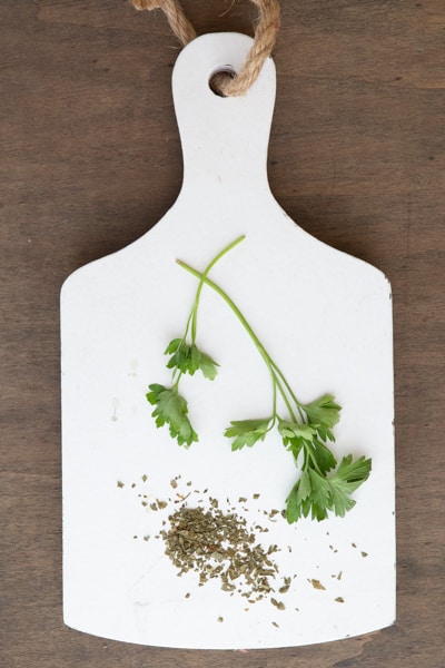 Parsley fresh and dried on a white board.