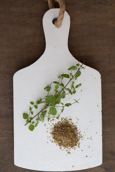 Oregano fresh and dried on a white board.