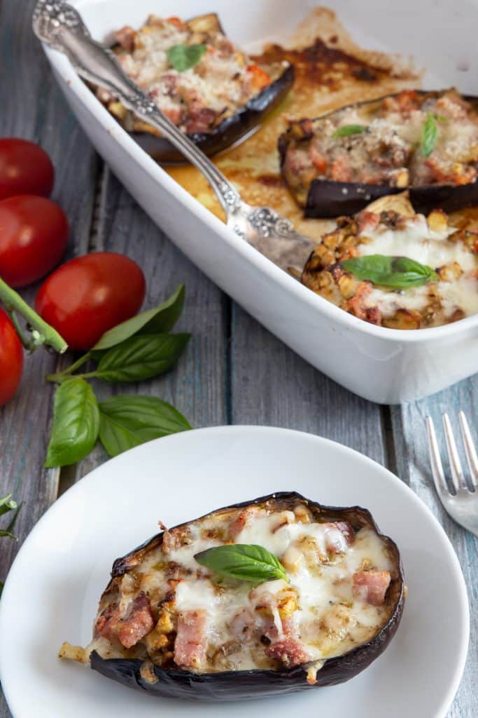 Eggplant boats in a white pan and one on a plate.
