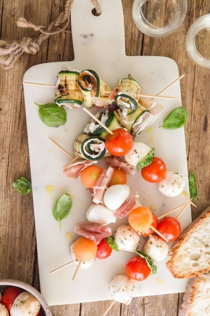 Antipasto skewers on a white board.