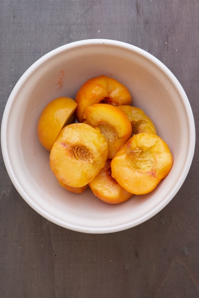 Halved peaches in a white bowl.