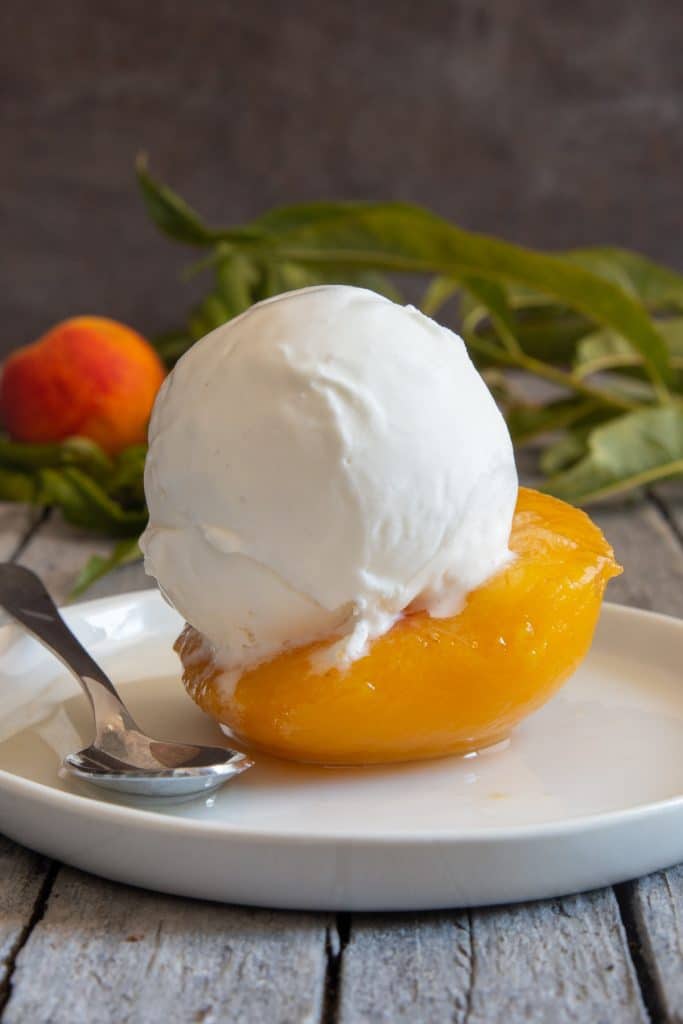 A scoop of ice cream on a peach half.
