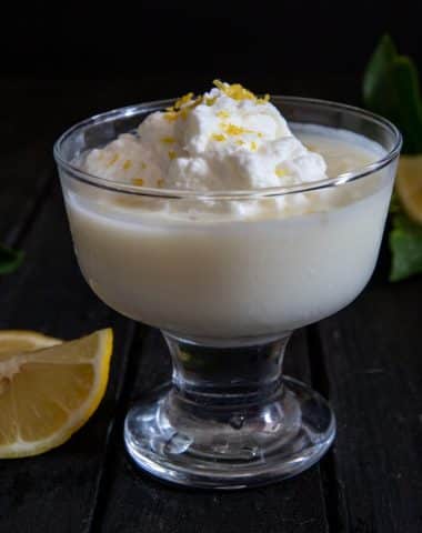 Pudding in a glass bowl with a dollop of whipped cream.