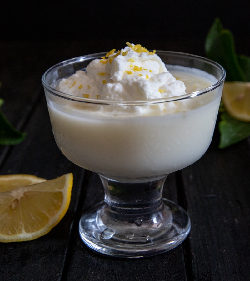Pudding in a glass bowl with a dollop of whipped cream.