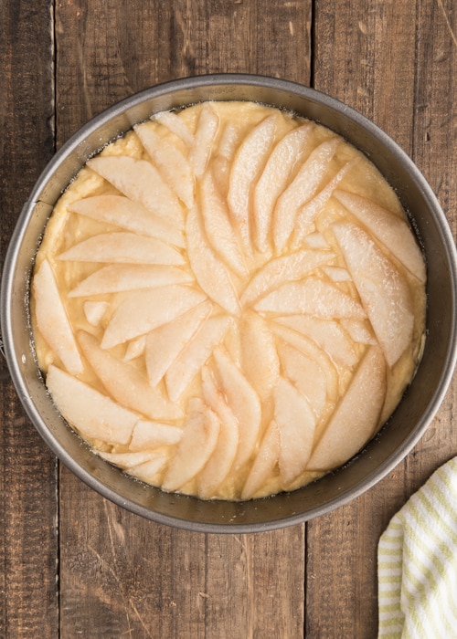 The batter in the cake pan with more pears, before baking.