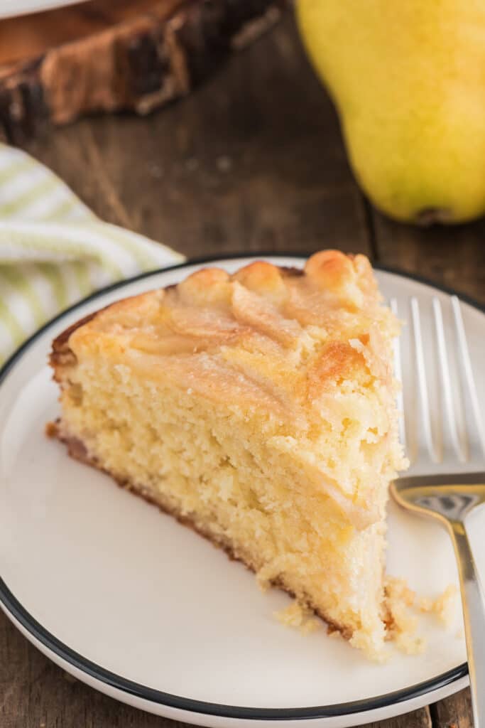 A slice of pear cake on a small white plate.