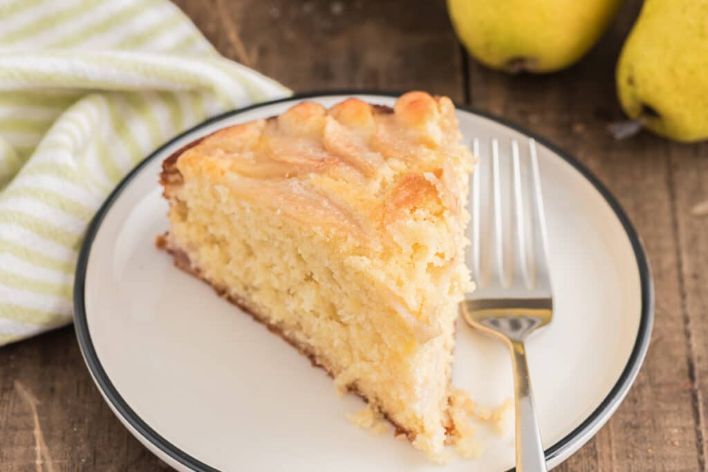 A slice of pear cake on a small white plate.