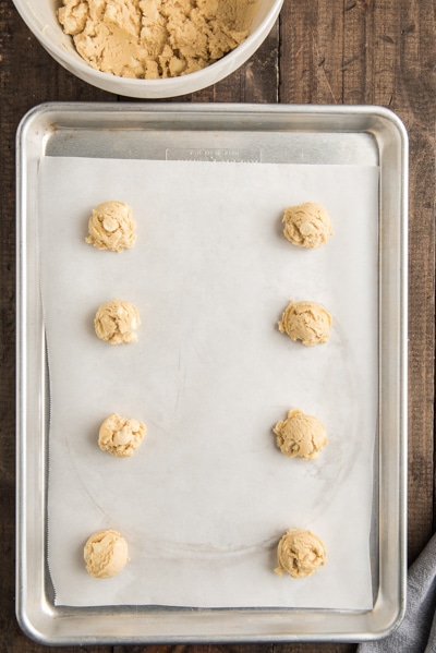 Cookie dough balls on a parchment paper cookie sheet.