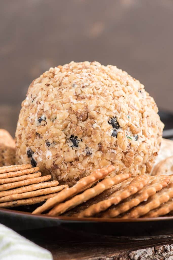 Cheese ball on a black plate with crackers.