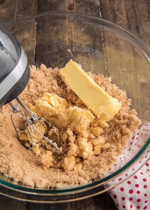 Beating the butter and brown sugar in a glass bowl.
