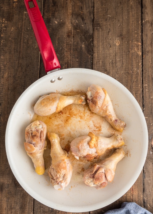 Browning the chicken in the white pan.