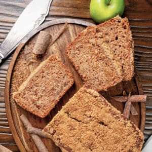 Applesauce bread with 3 slices cut on a wooden plate.