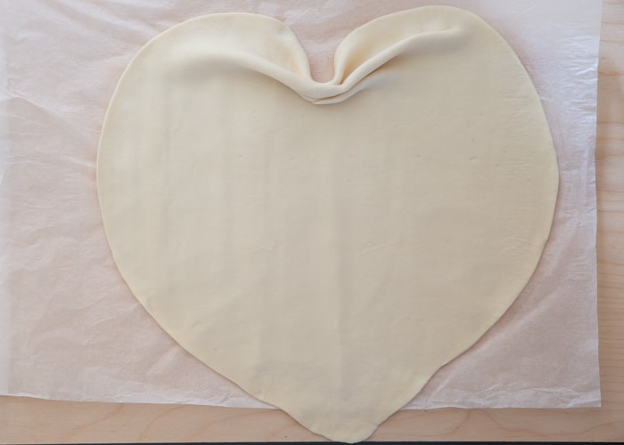 Dough shaped like a heart on parchment paper.