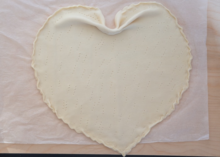 Dough shaped like a heart with a border and pricked with a fork.
