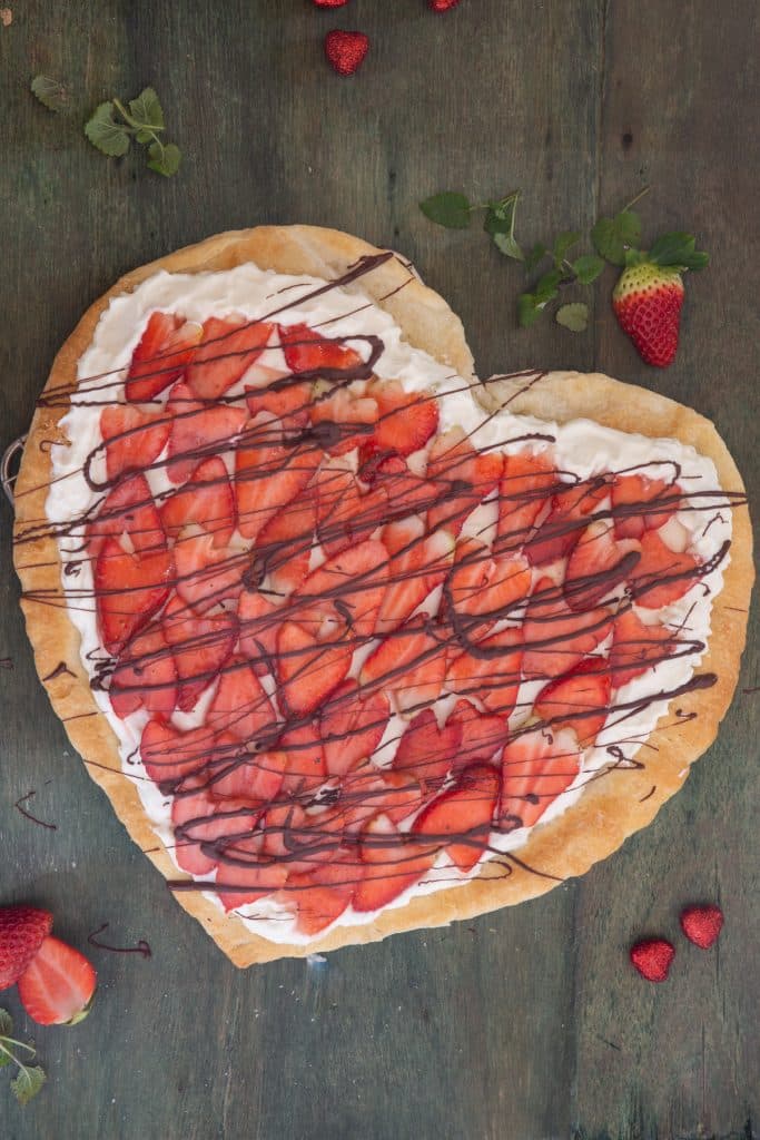 Heart strawberry pie on a green board.