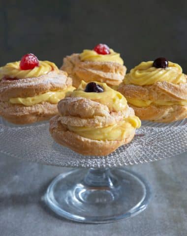 Four pastries on a a glass cake stand.